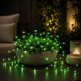 Potted plant with green LED lights on a dark surface, candle in the background