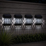 Four solar-powered outdoor lights on a wooden surface with shadows.