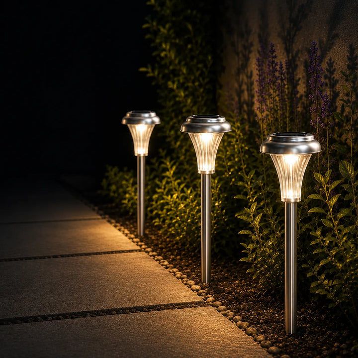 Three solar-powered garden lights illuminating a pathway at night.