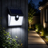 Solar-powered outdoor light fixture on a wooden wall with pathway and garden in the background